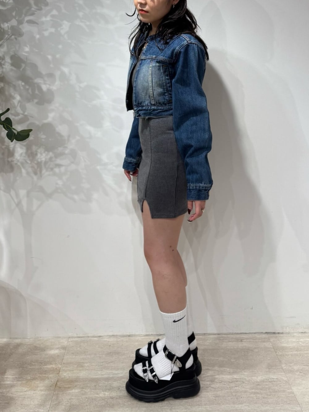 グレー系のワンピース、ブルー系のデニムジャケット、ブラック系のサンダルを着用したレディースの春コーディネートの2枚目の写真