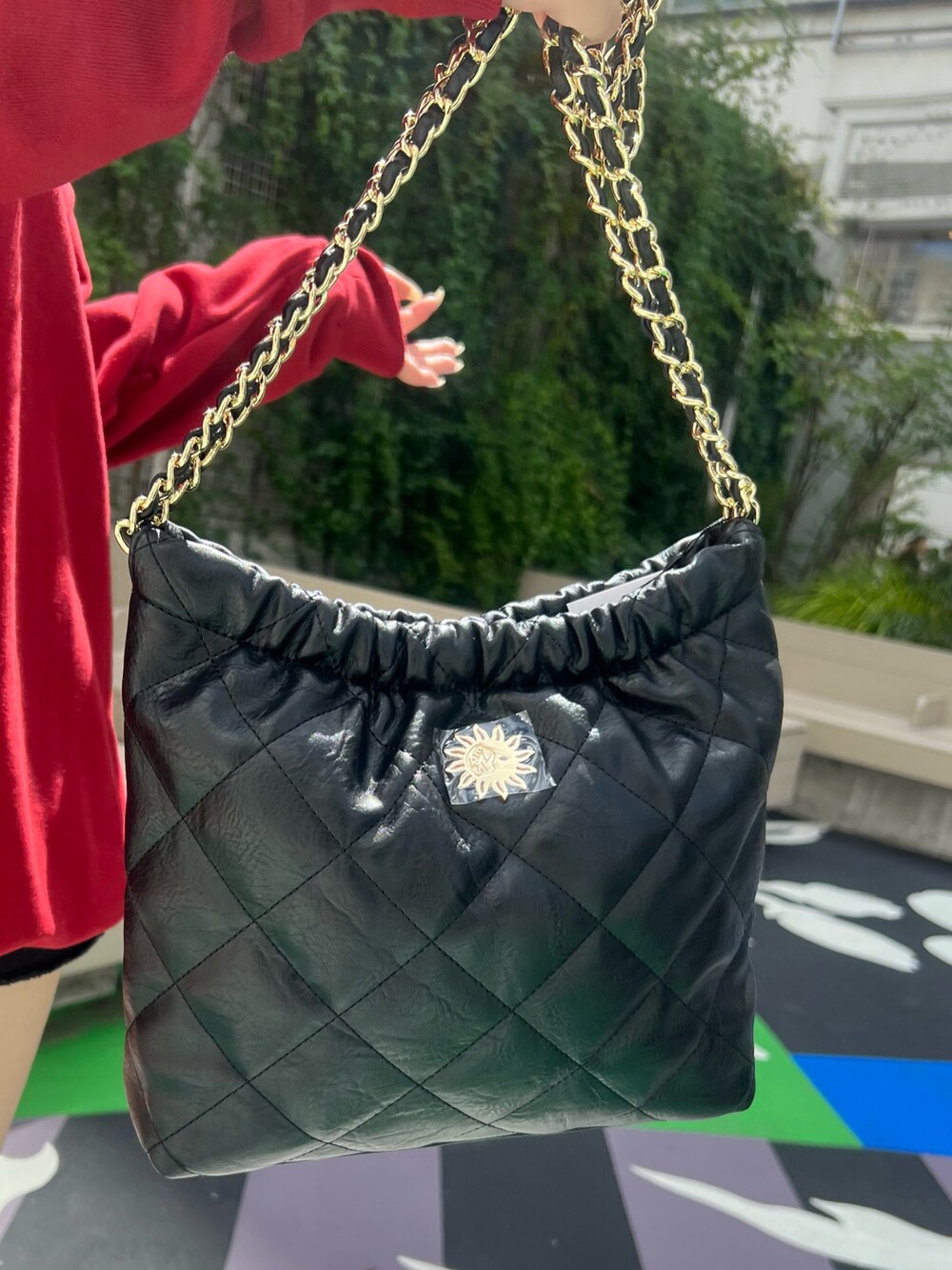 レッド系のスウェット、ブラック系のショルダーバッグ、ブラック系のブーツを着用したレディースの夏コーディネートの8枚目の写真