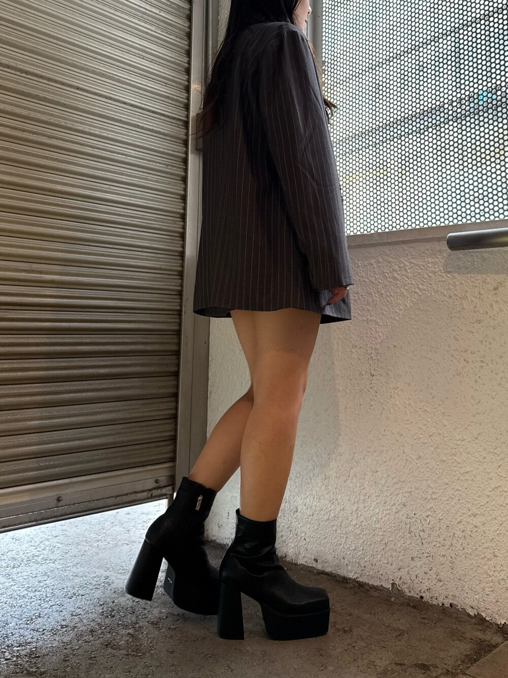 グレー系のテーラードジャケット、グレー系のスカート、ブラック系のブーツを着用したレディースの秋コーディネートの3枚目の写真