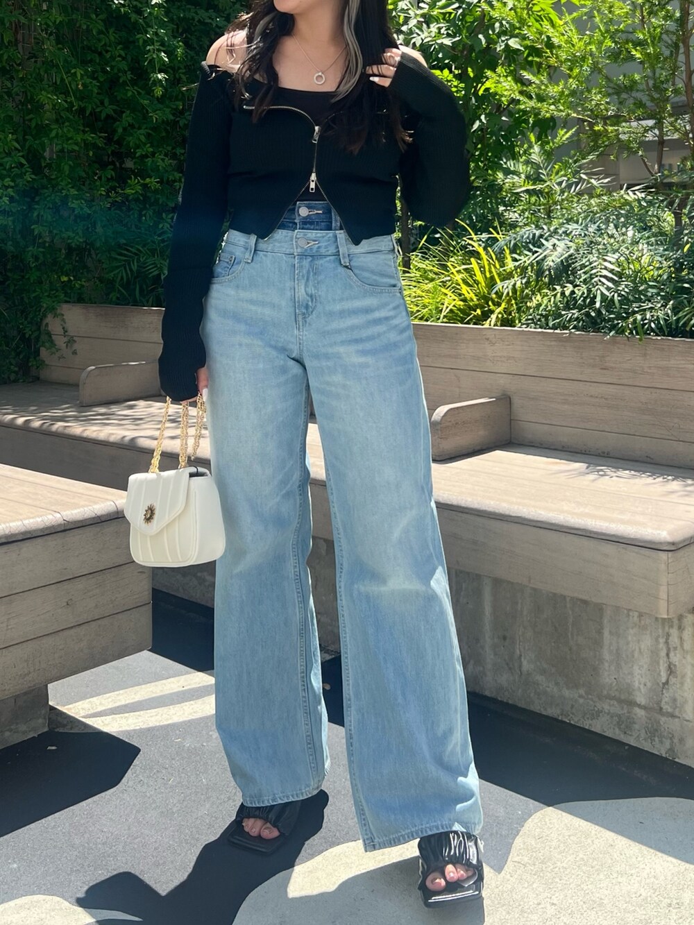 ブルー系のデニムパンツ、ブラック系のニット/セーター、ブラック系のサンダルを着用したレディースの夏コーディネートの3枚目の写真