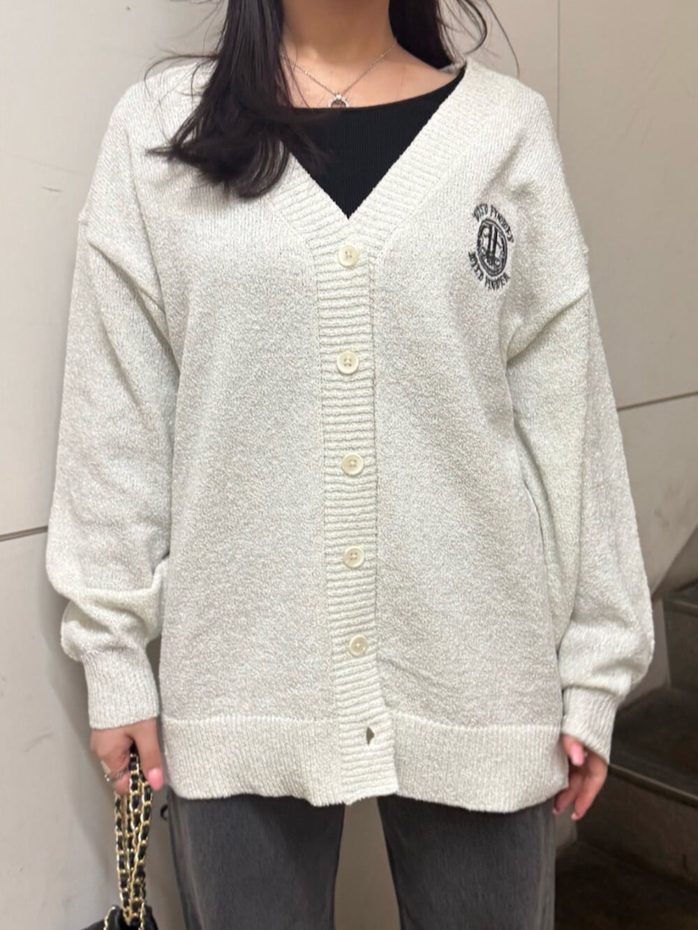 グレー系のニット/セーター、ホワイト系のカーディガン/ボレロ、ブラック系のデニムパンツを着用したレディースの春コーディネートの5枚目の写真