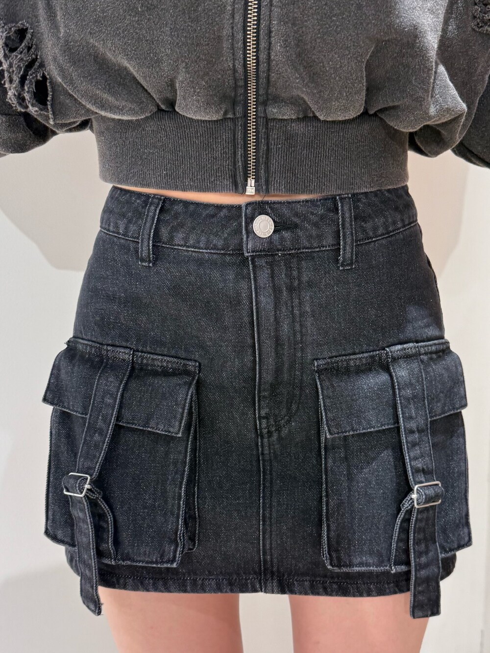 ブラック系のデニムスカート、ブラック系のブーツ、ブラック系のパーカーを着用したレディースの春コーディネートの5枚目の写真