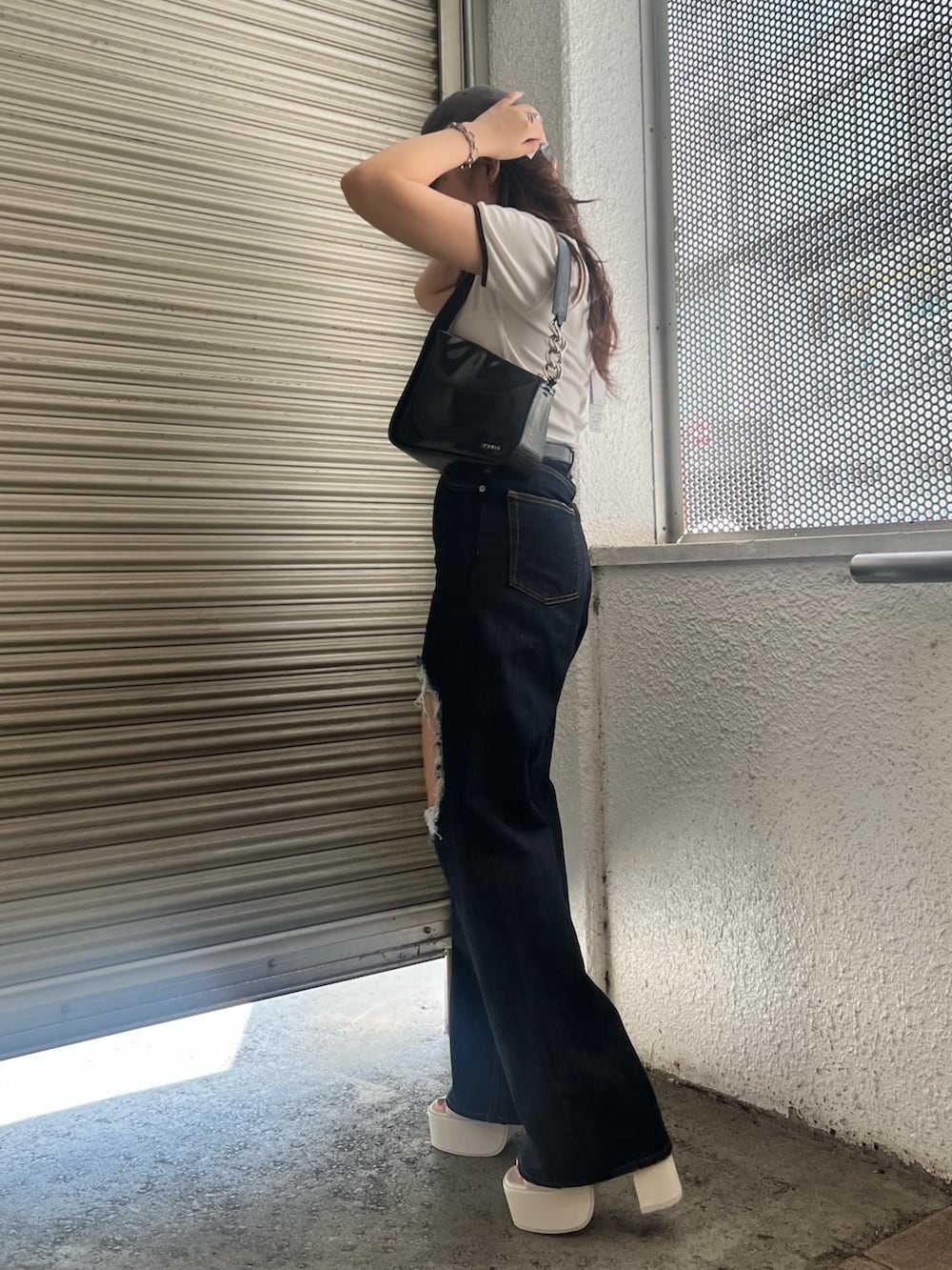 ブルー系のデニムパンツ、ホワイト系のTシャツ/カットソー、ブラック系のハンドバッグを着用したレディースの夏コーディネートの3枚目の写真