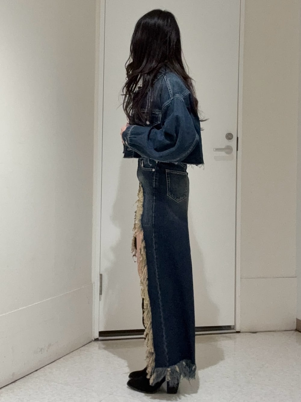 ブルー系のデニムジャケット、ブラック系のブーツ、ブルー系のデニムスカートを着用したレディースの冬コーディネートの2枚目の写真