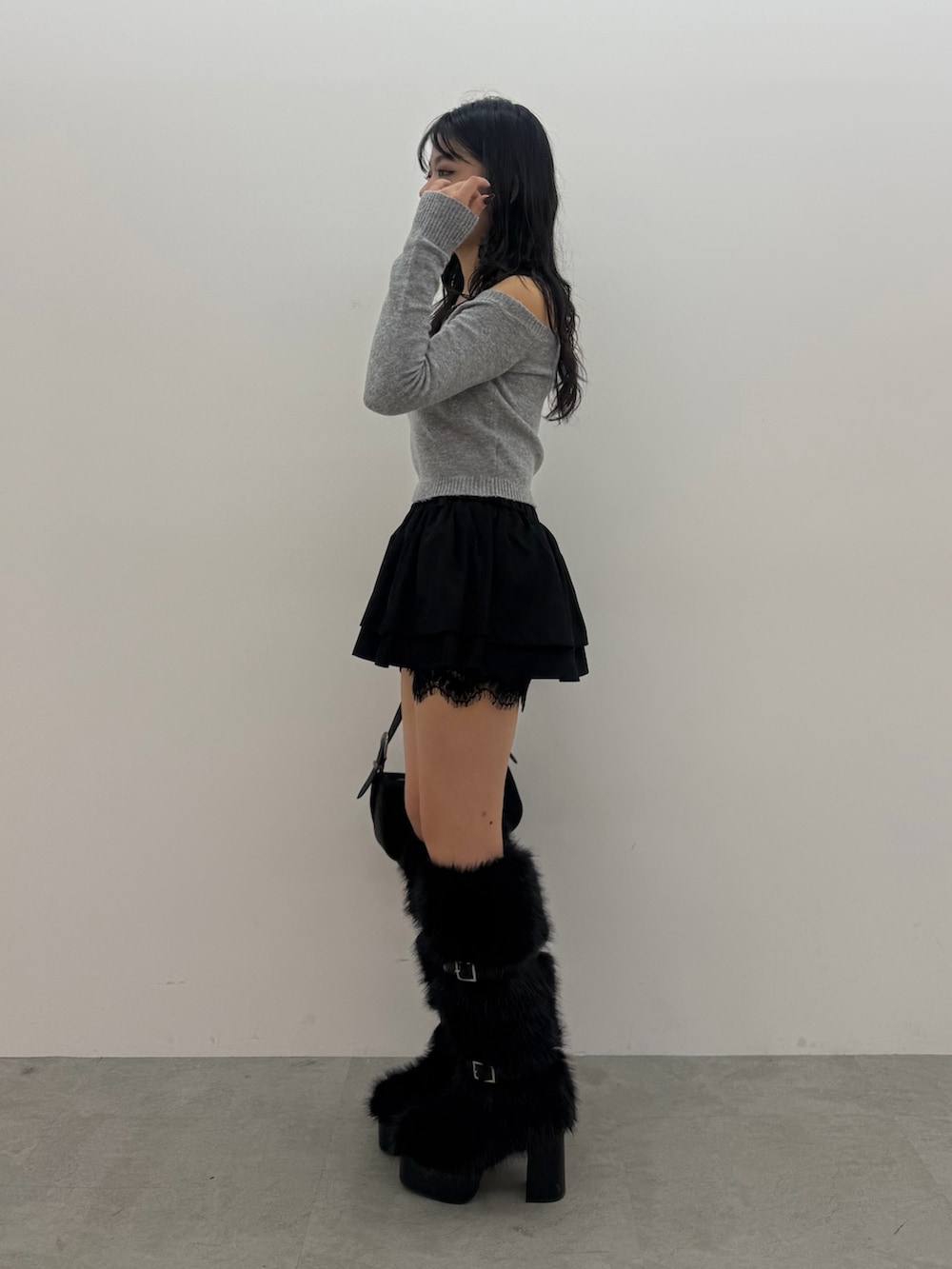 グレー系のニット/セーター、ブラック系のスカート、ブラック系のブーツを着用したレディースの秋コーディネートの2枚目の写真