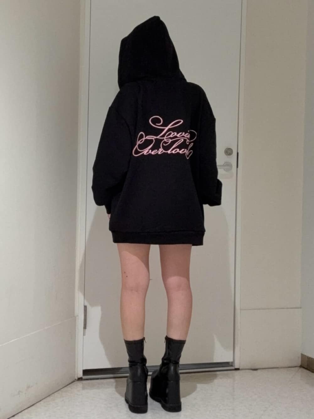 ブラック系のブーツ、ブラック系のパーカー、ブラック系のキャップを着用したレディースの春コーディネートの3枚目の写真