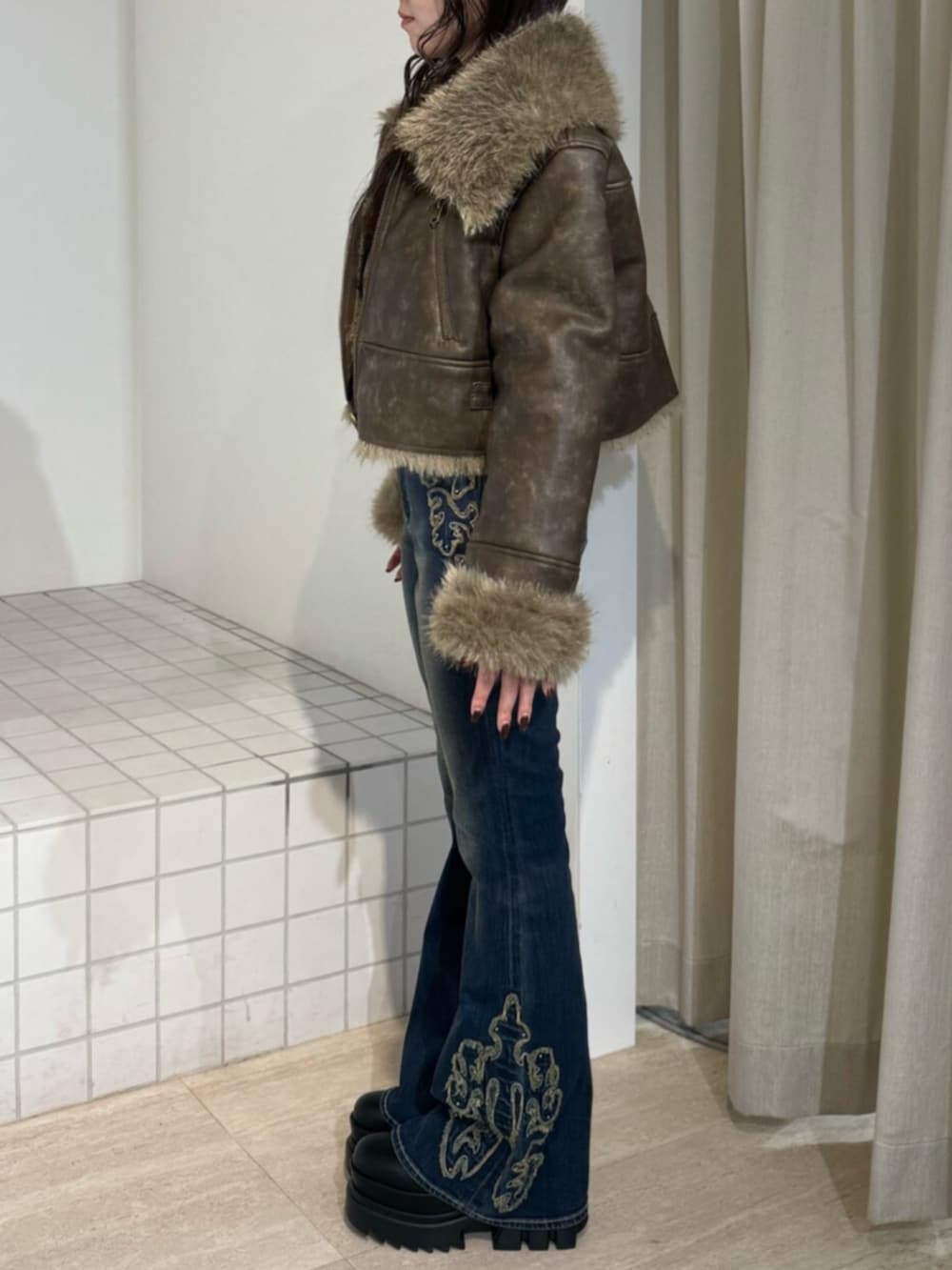 ブルー系のデニムパンツ、ブラック系のブーツ、ブラウン系のブルゾンを着用したレディースの秋コーディネートの2枚目の写真