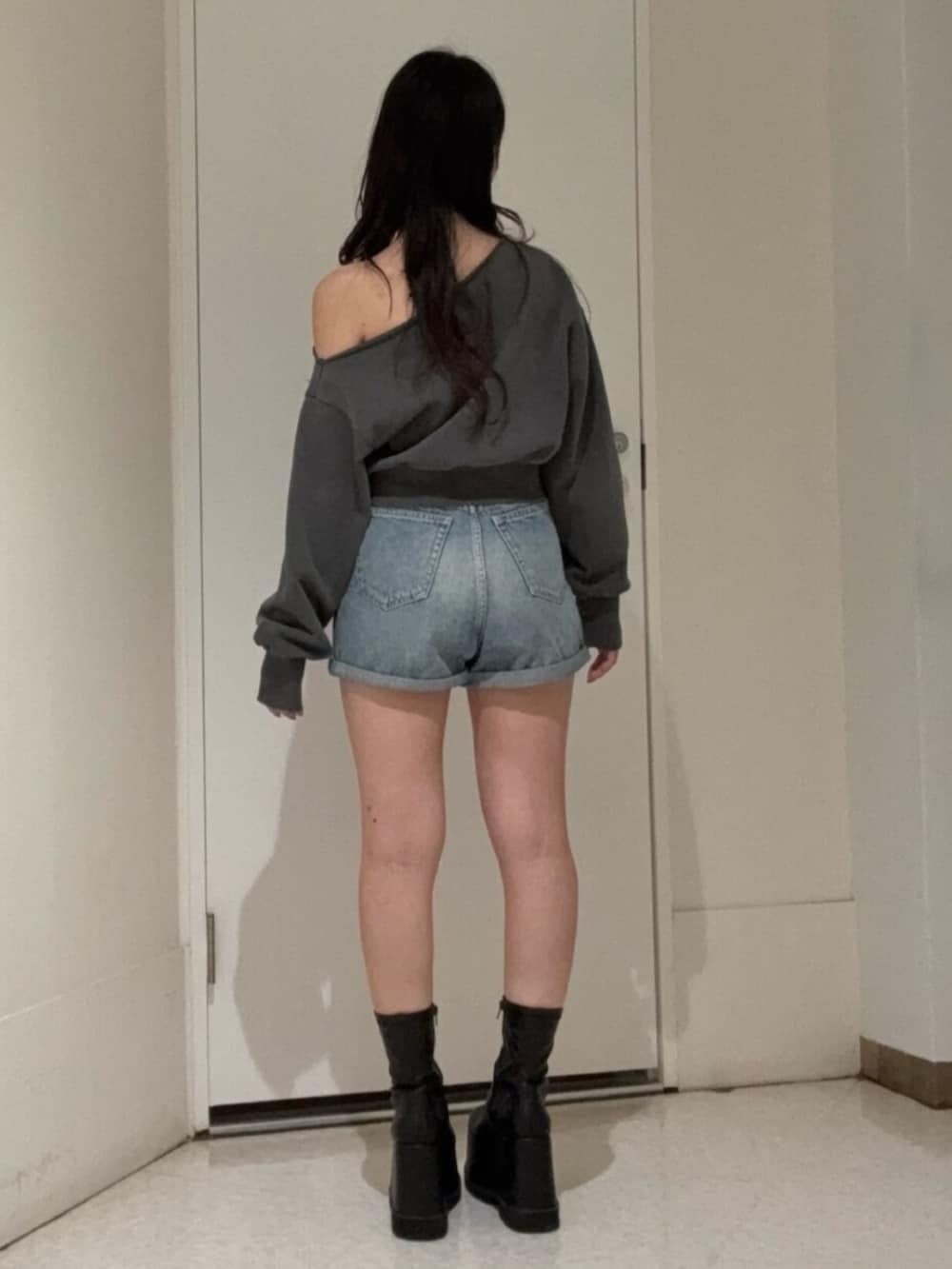 ブラック系のブーツ、ブルー系のデニムパンツ、ブラック系のスウェットを着用したレディースの冬コーディネートの3枚目の写真