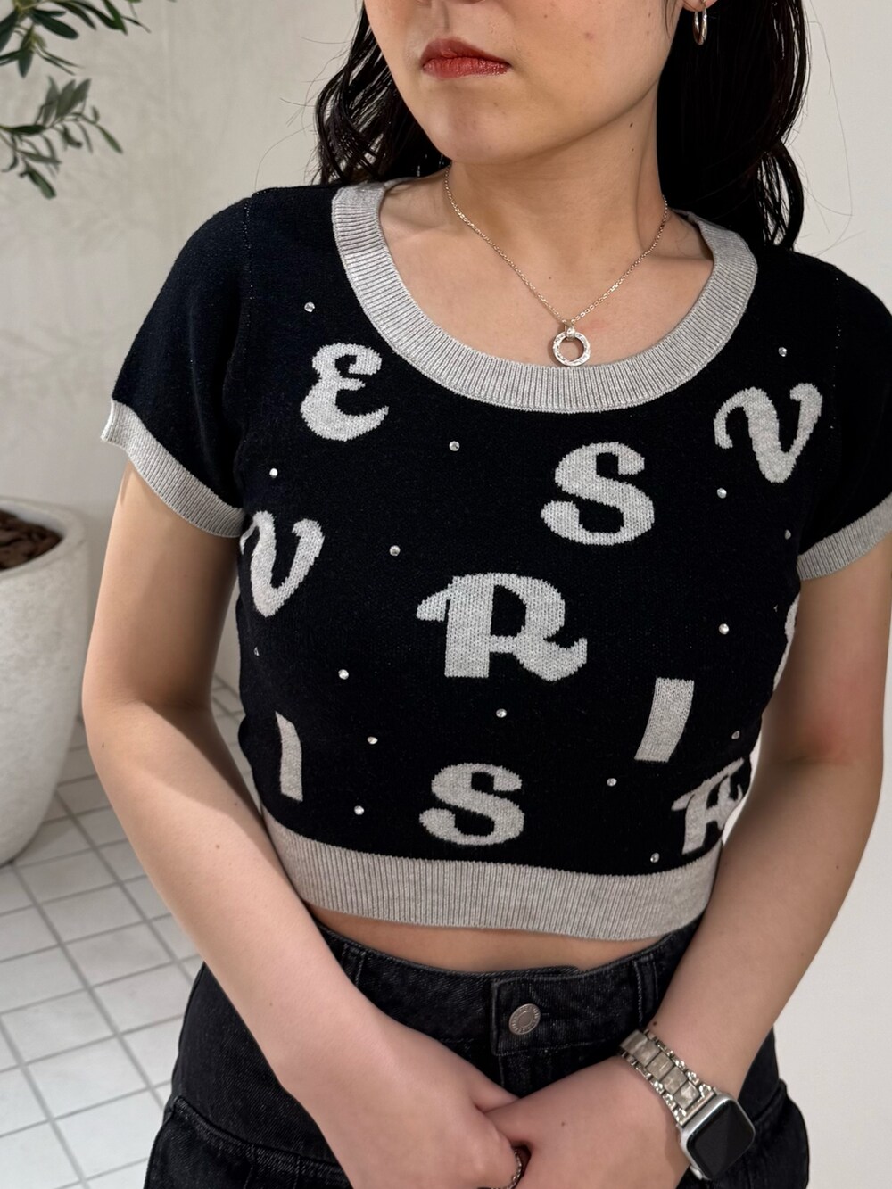 ブラック系のニット/セーター、ブラック系のデニムスカート、ブラック系のブーツを着用したレディースの春コーディネートの4枚目の写真