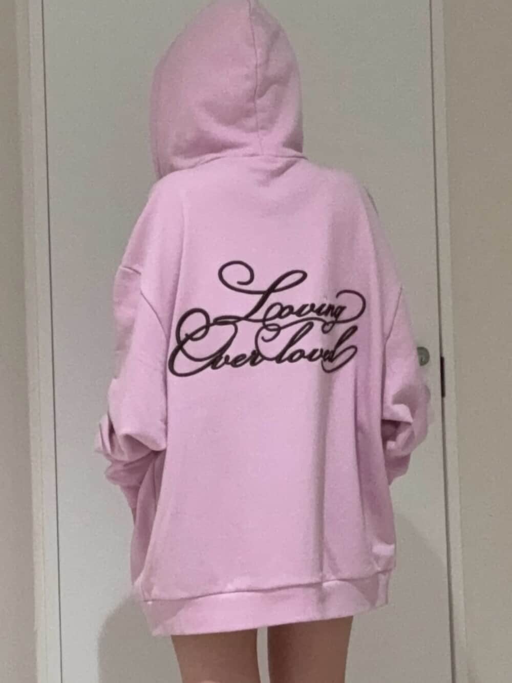 ブラック系のブーツ、ピンク系のパーカー、ブラック系のキャップを着用したレディースの春コーディネートの4枚目の写真