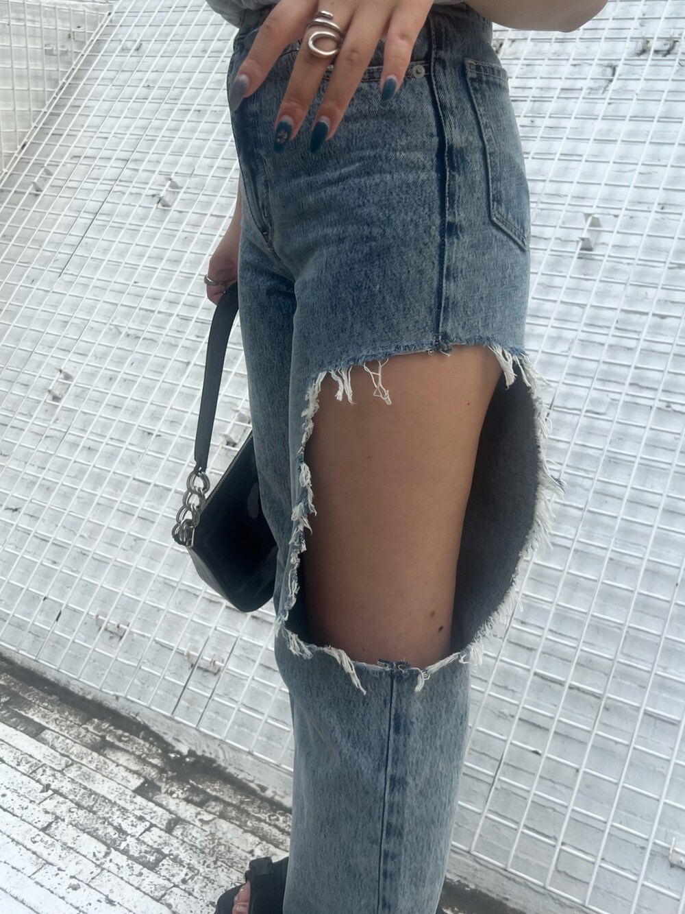 ブルー系のデニムパンツ、ブラック系のハンドバッグ、グレー系のタンクトップを着用したレディースの夏コーディネートの5枚目の写真