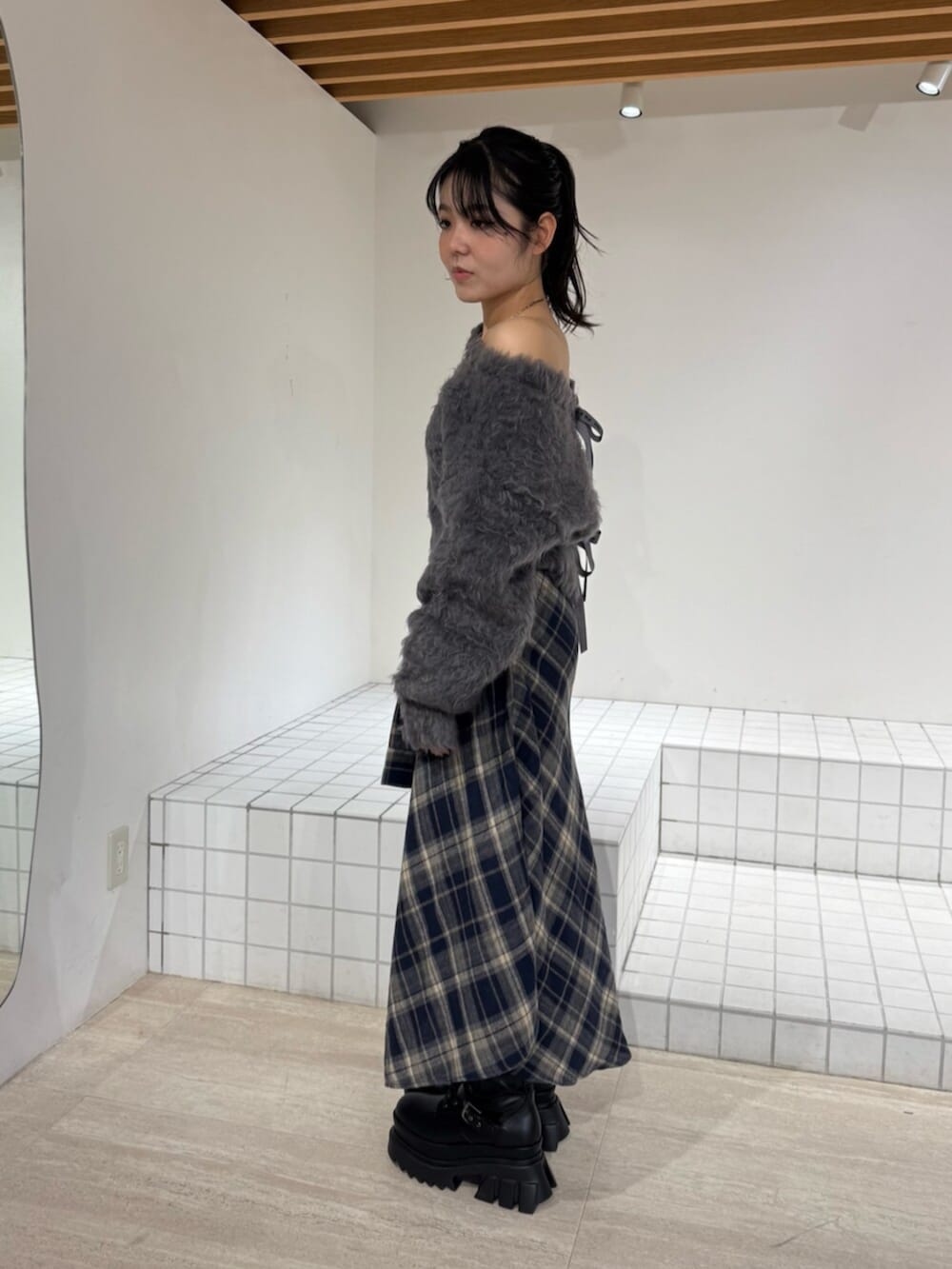 ブルー系のスカート、ブラック系のブーツ、グレー系のニット/セーターを着用したレディースの秋コーディネートの2枚目の写真