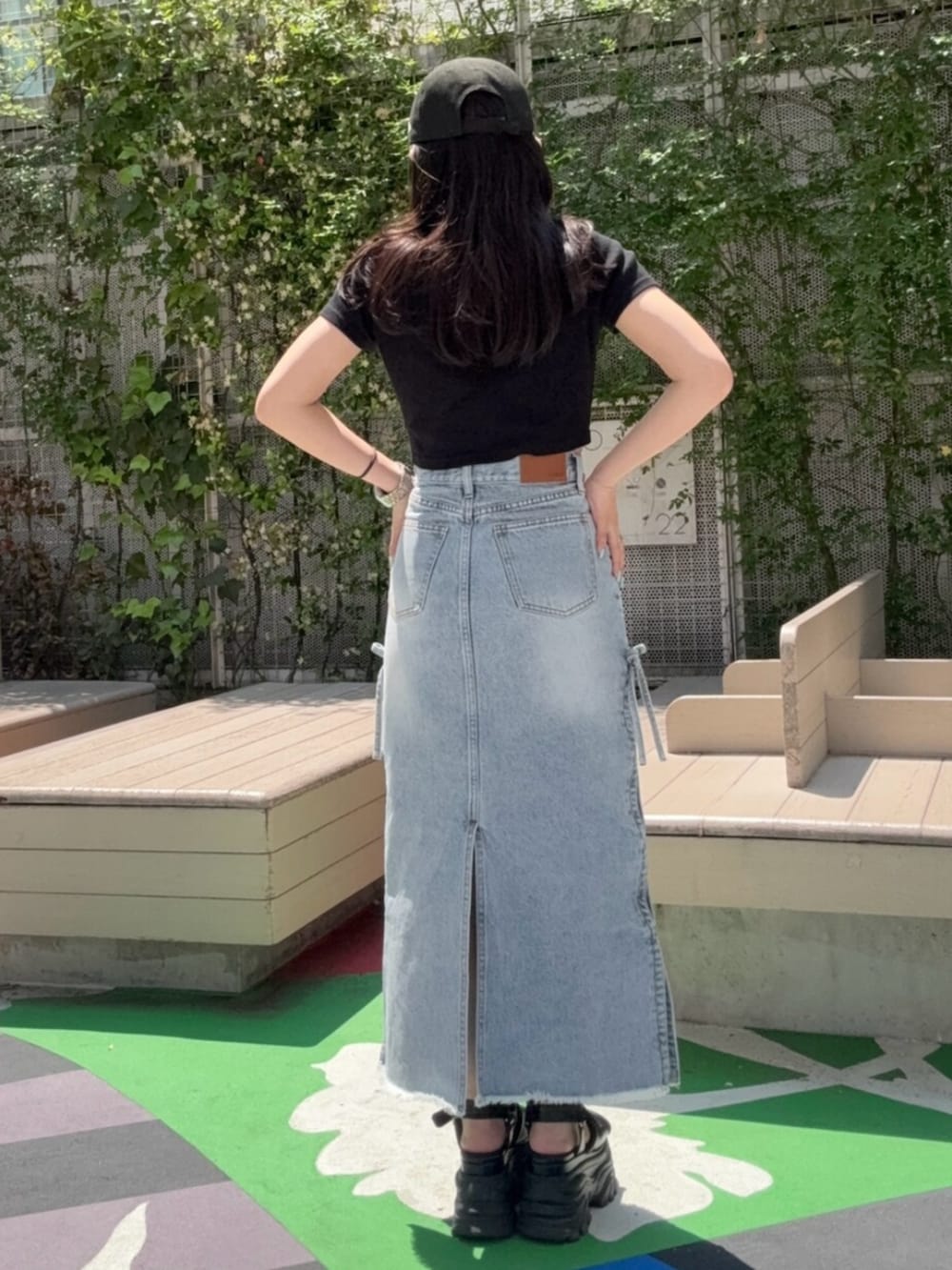 ブラウン系のサンダル、ブルー系のデニムスカート、ブラック系のTシャツ/カットソーを着用したレディースの春コーディネートの3枚目の写真