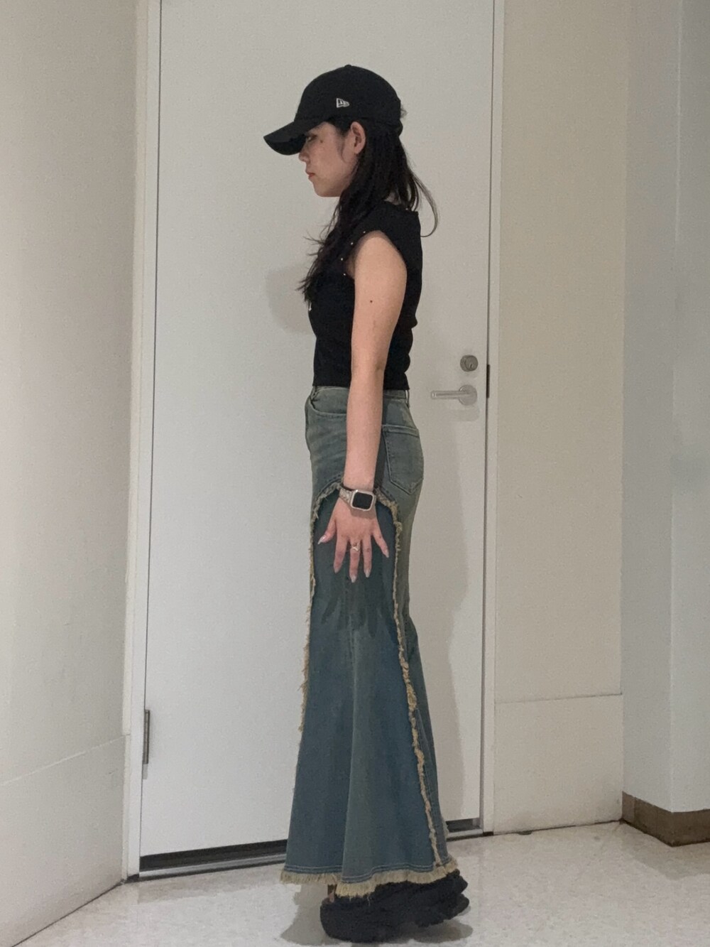 ブラック系のタンクトップ、ブルー系のデニムスカート、ブラウン系のサンダルを着用したレディースの夏コーディネートの2枚目の写真