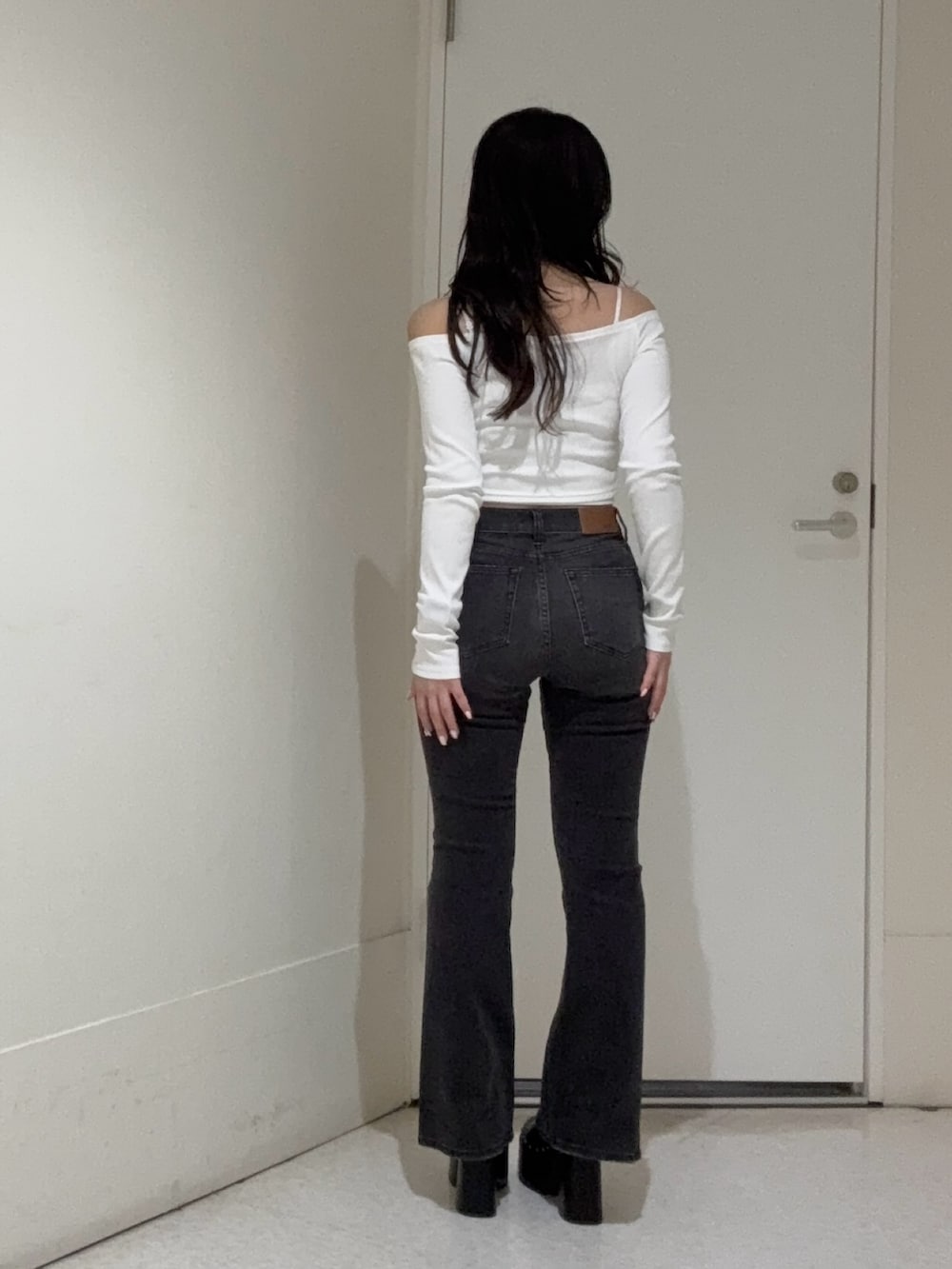 ブラック系のデニムパンツ、ホワイト系のTシャツ/カットソー、ブラック系のサンダルを着用したレディースの春コーディネートの3枚目の写真