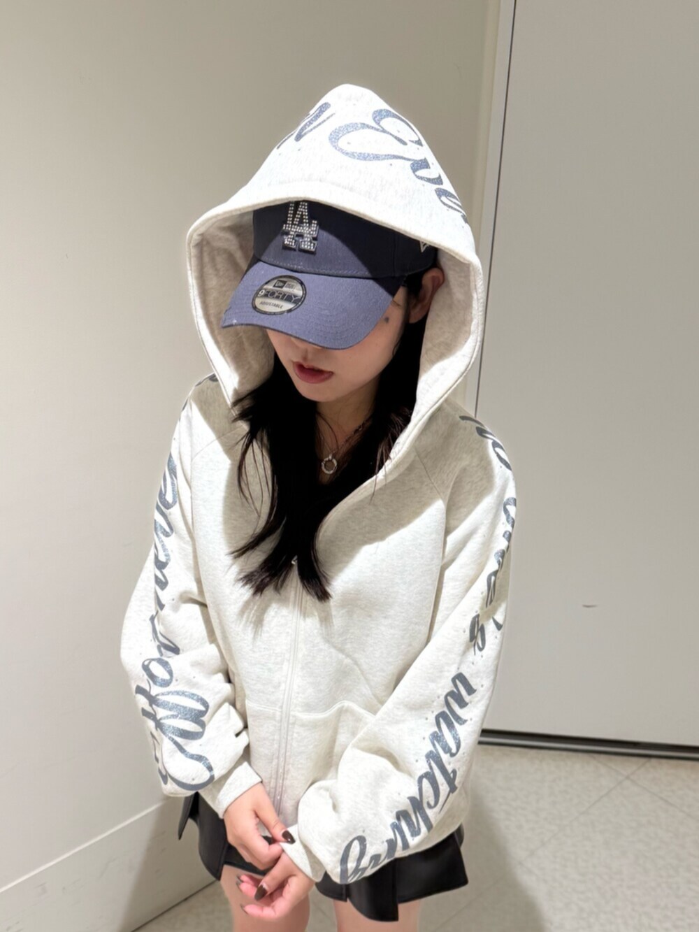 ブラック系のブーツ、ブラック系のスカート、グレー系のパーカーを着用したレディースの秋コーディネートの4枚目の写真