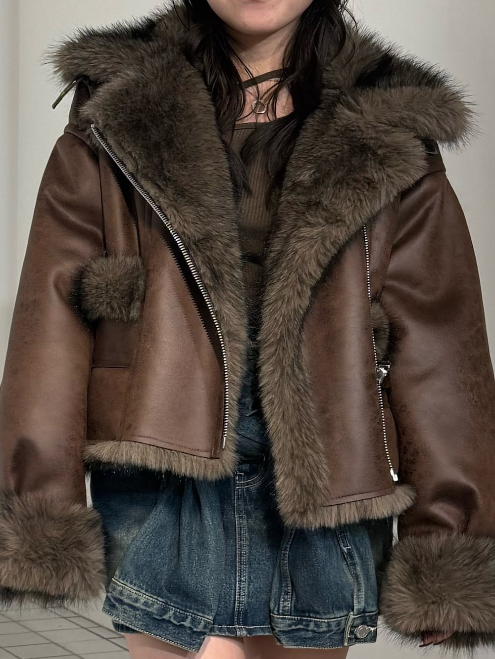 ブラウン系のブルゾン、ブルー系のデニムスカート、ブラック系のブーツを着用したレディースの秋コーディネートの4枚目の写真