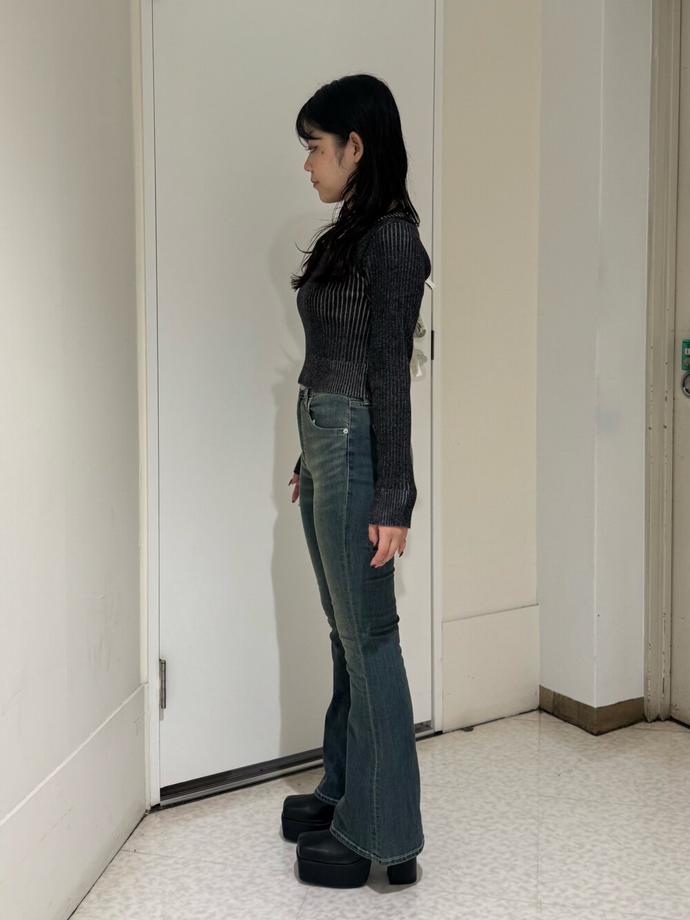 ブルー系のデニムパンツ、ブラック系のニット/セーター、ブラック系のブーツを着用したレディースの秋コーディネートの2枚目の写真