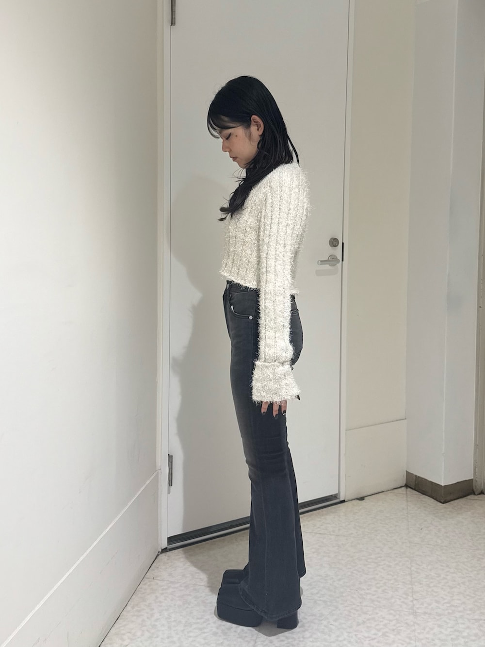 ブラック系のブーツ、ブラック系のデニムパンツ、ホワイト系のカーディガン/ボレロを着用したレディースの秋コーディネートの2枚目の写真