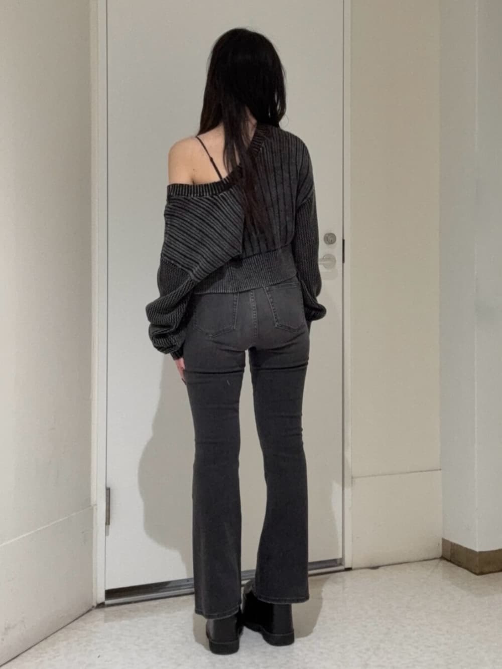 ブラック系のデニムパンツ、ブラック系のブーツ、ホワイト系のカーディガン/ボレロを着用したレディースの春コーディネートの3枚目の写真