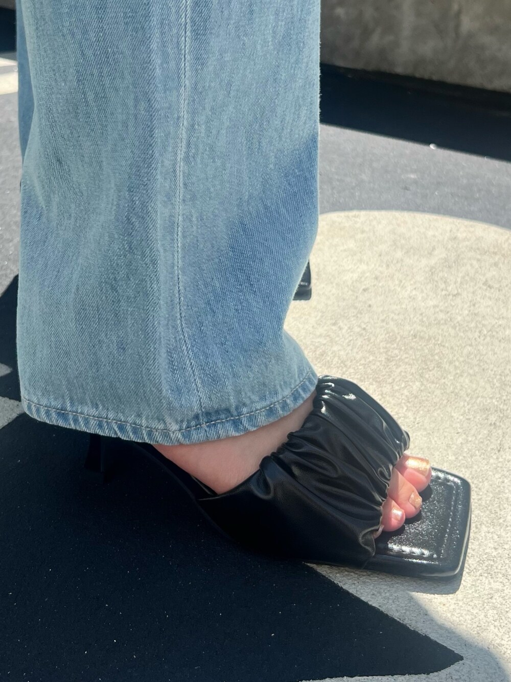 ブルー系のデニムパンツ、ブラック系のニット/セーター、ブラック系のサンダルを着用したレディースの夏コーディネートの9枚目の写真