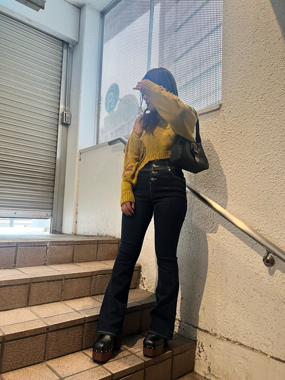 ブルー系のデニムパンツ、ブラック系のサンダル、ブラック系のハンドバッグを着用したレディースの春コーディネートの2枚目の写真