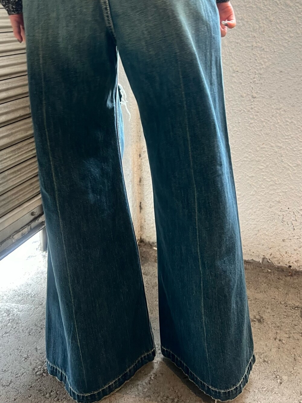 ブルー系のデニムパンツ、ホワイト系のブーツ、ブラック系のニット/セーターを着用したレディースの春コーディネートの7枚目の写真