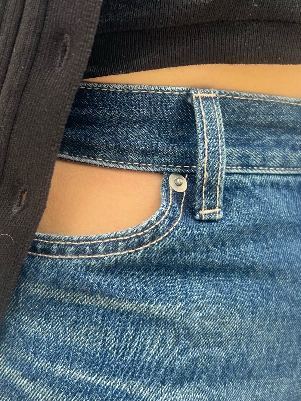 ブルー系のデニムパンツ、ブラック系のニット/セーター、ブラック系のハンドバッグを着用したレディースの春コーディネートの6枚目の写真