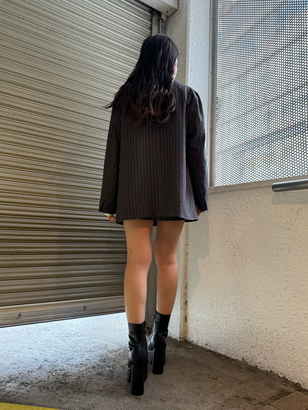 グレー系のテーラードジャケット、グレー系のスカート、ブラック系のブーツを着用したレディースの秋コーディネートの4枚目の写真