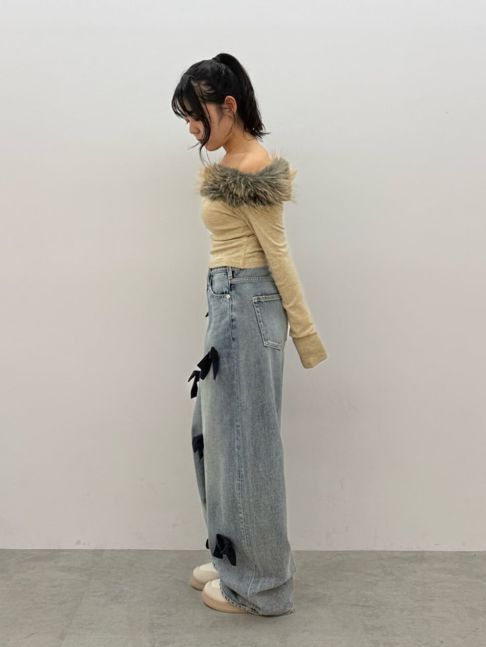 ベージュ系のTシャツ/カットソー、ブルー系のデニムパンツ、ホワイト系のスニーカーを着用したレディースの秋コーディネートの2枚目の写真