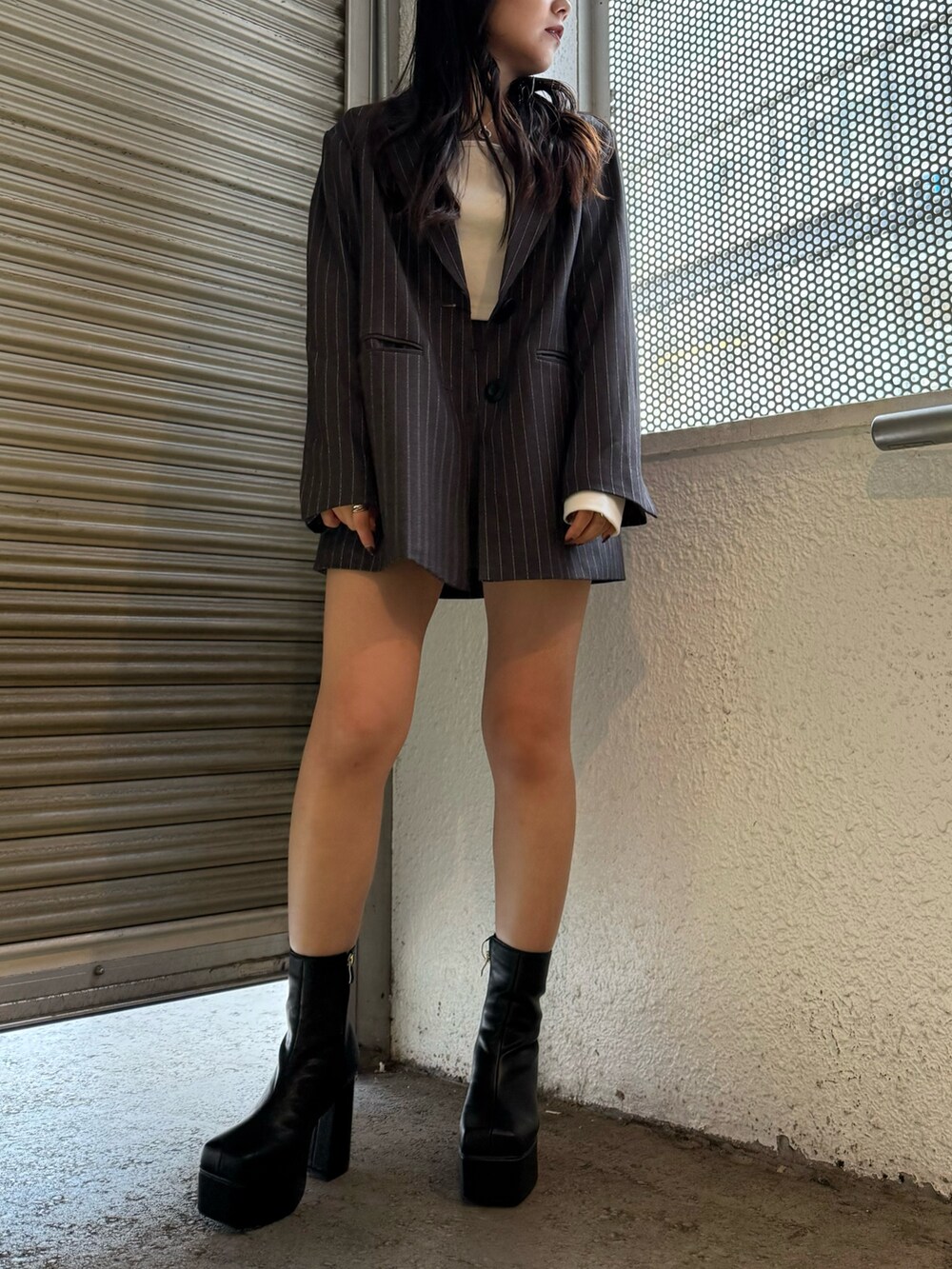 グレー系のテーラードジャケット、グレー系のスカート、ブラック系のブーツを着用したレディースの秋コーディネートの2枚目の写真