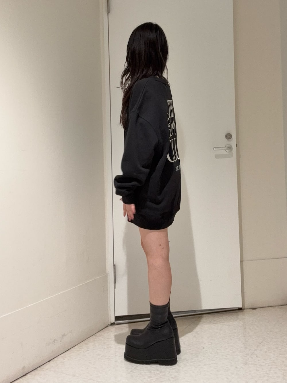 ブラック系のスウェット、ブラック系のブーツ、ブルー系のデニムパンツを着用したレディースの冬コーディネートの2枚目の写真