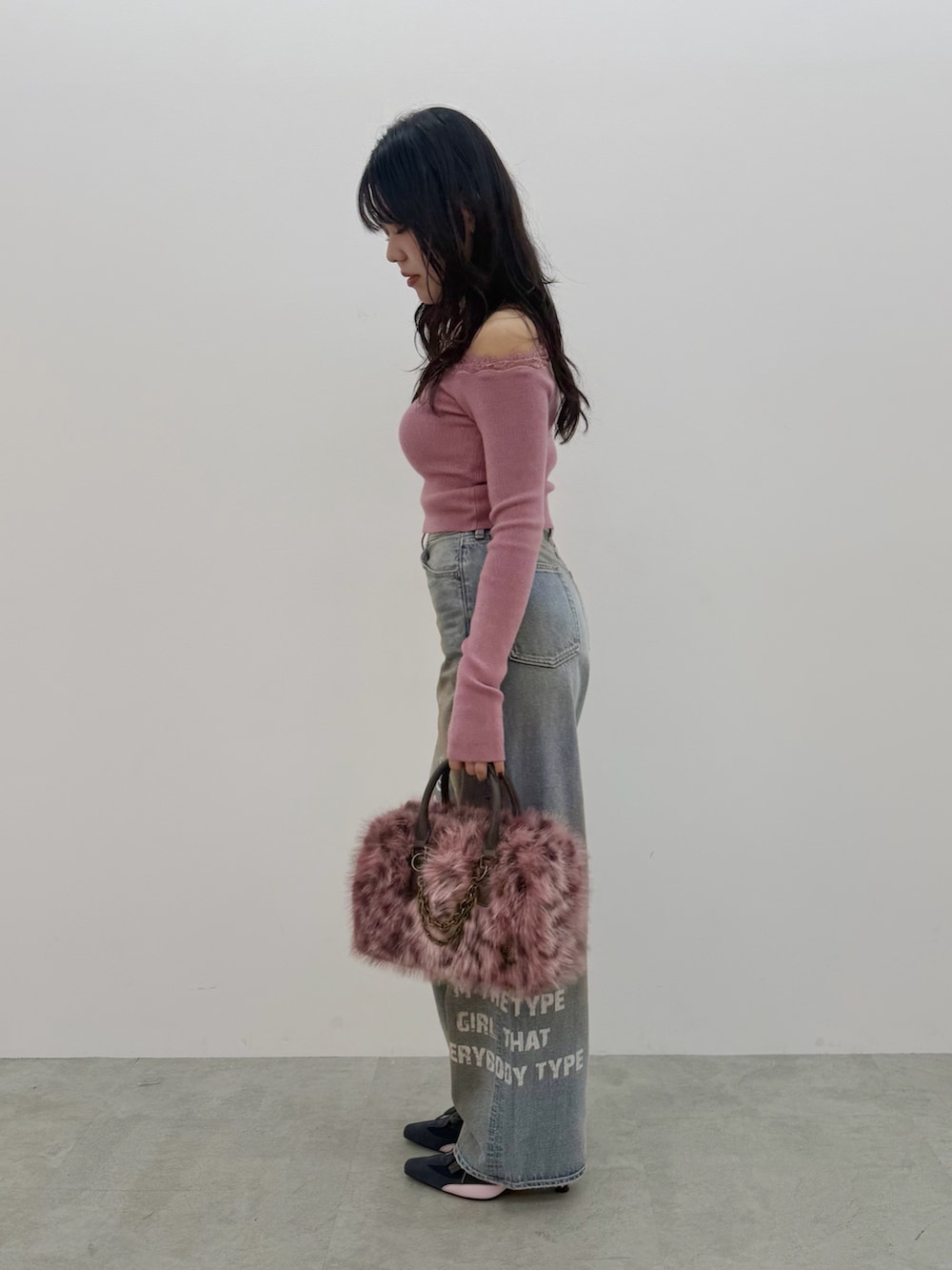 ピンク系のボストンバッグ、ピンク系のニット/セーター、ブルー系のデニムパンツを着用したレディースの秋コーディネートの2枚目の写真