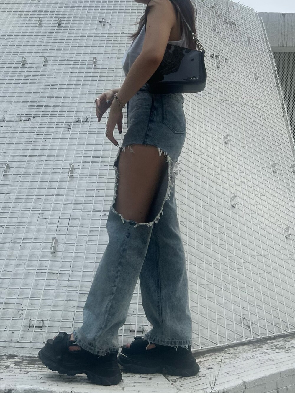 ブルー系のデニムパンツ、ブラック系のハンドバッグ、グレー系のタンクトップを着用したレディースの夏コーディネートの3枚目の写真