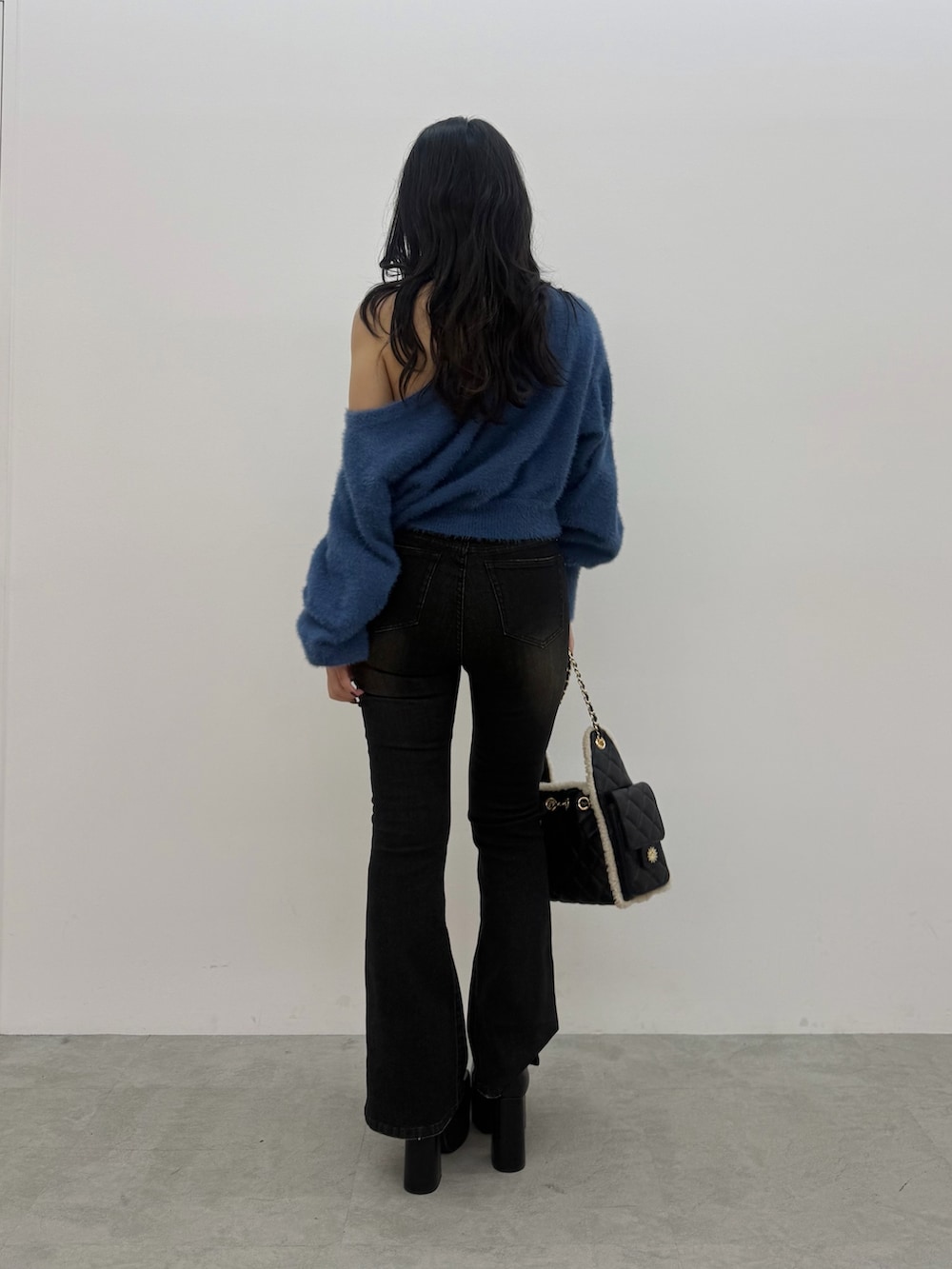 ブルー系のニット/セーター、ブラック系のデニムパンツ、ブラック系のブーツを着用したレディースの秋コーディネートの3枚目の写真