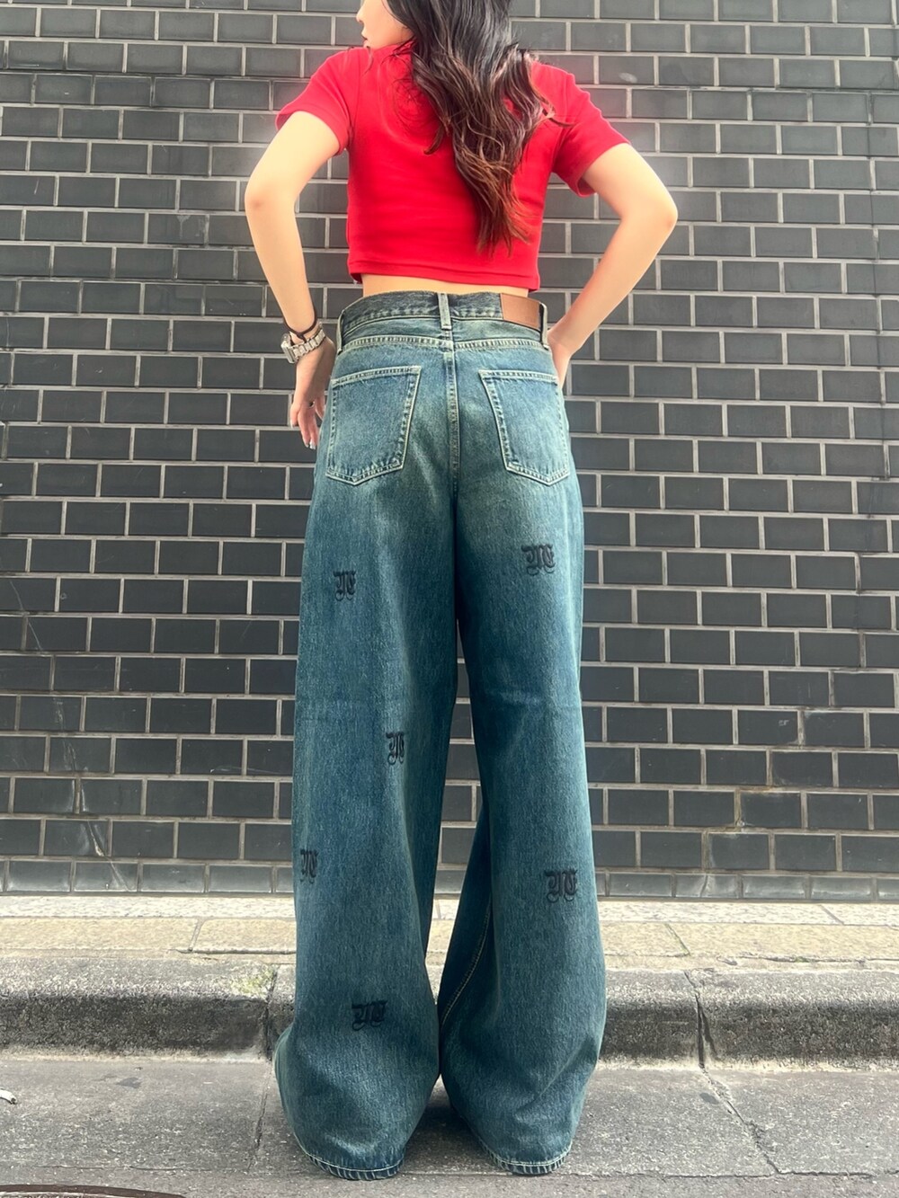 レッド系のTシャツ/カットソー、ブルー系のデニムパンツ、ブラック系のサンダルを着用したレディースの春コーディネートの4枚目の写真