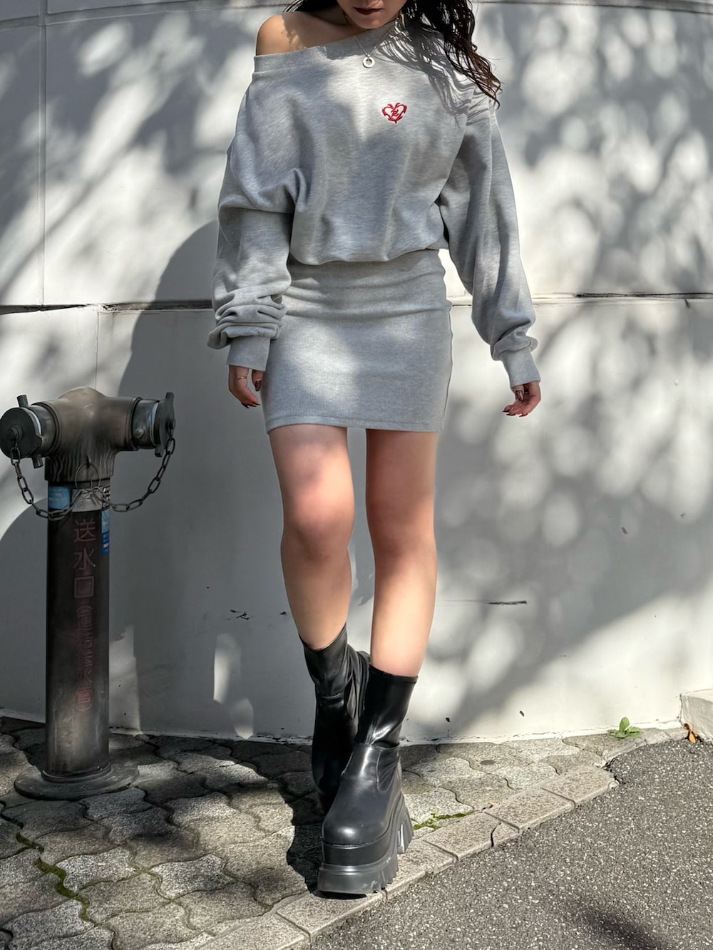 グレー系のワンピース、ブラック系のブーツを着用したレディースの秋コーディネートの2枚目の写真