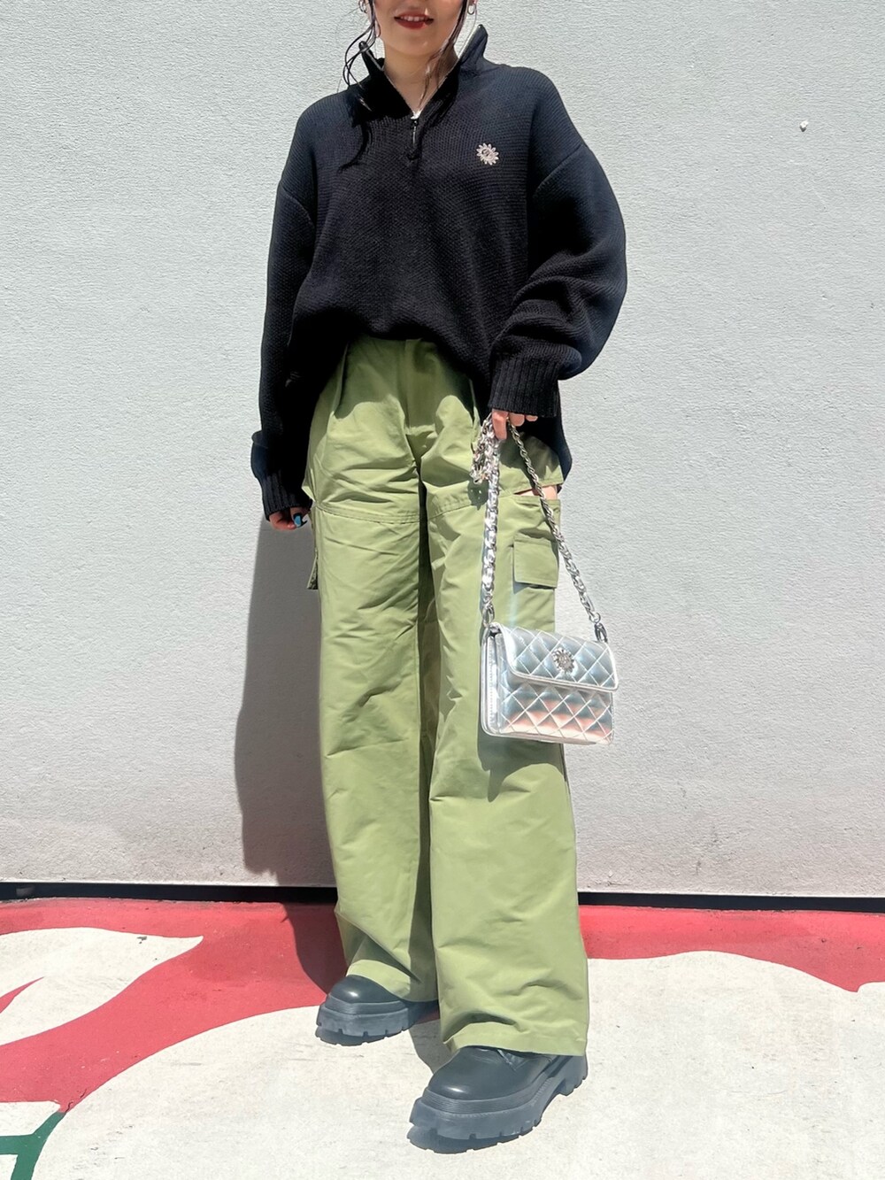 グリーン系のカーゴパンツ、ブラック系のショルダーバッグ、ブラック系のブーツを着用したレディースの夏コーディネートの2枚目の写真