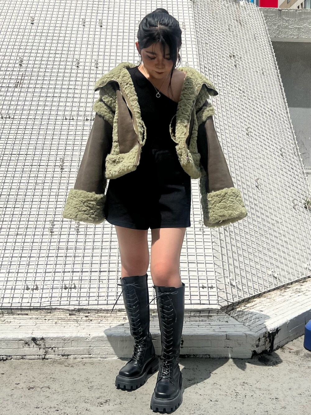 ブラック系のその他パンツ、ブラック系のブーツ、グリーン系のムートンコートを着用したレディースの夏コーディネートの3枚目の写真