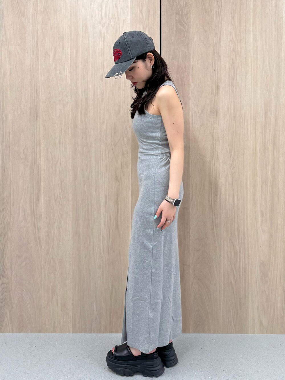 グレー系のワンピース、ブラウン系のサンダル、ブラック系のキャップを着用したレディースの春コーディネートの2枚目の写真