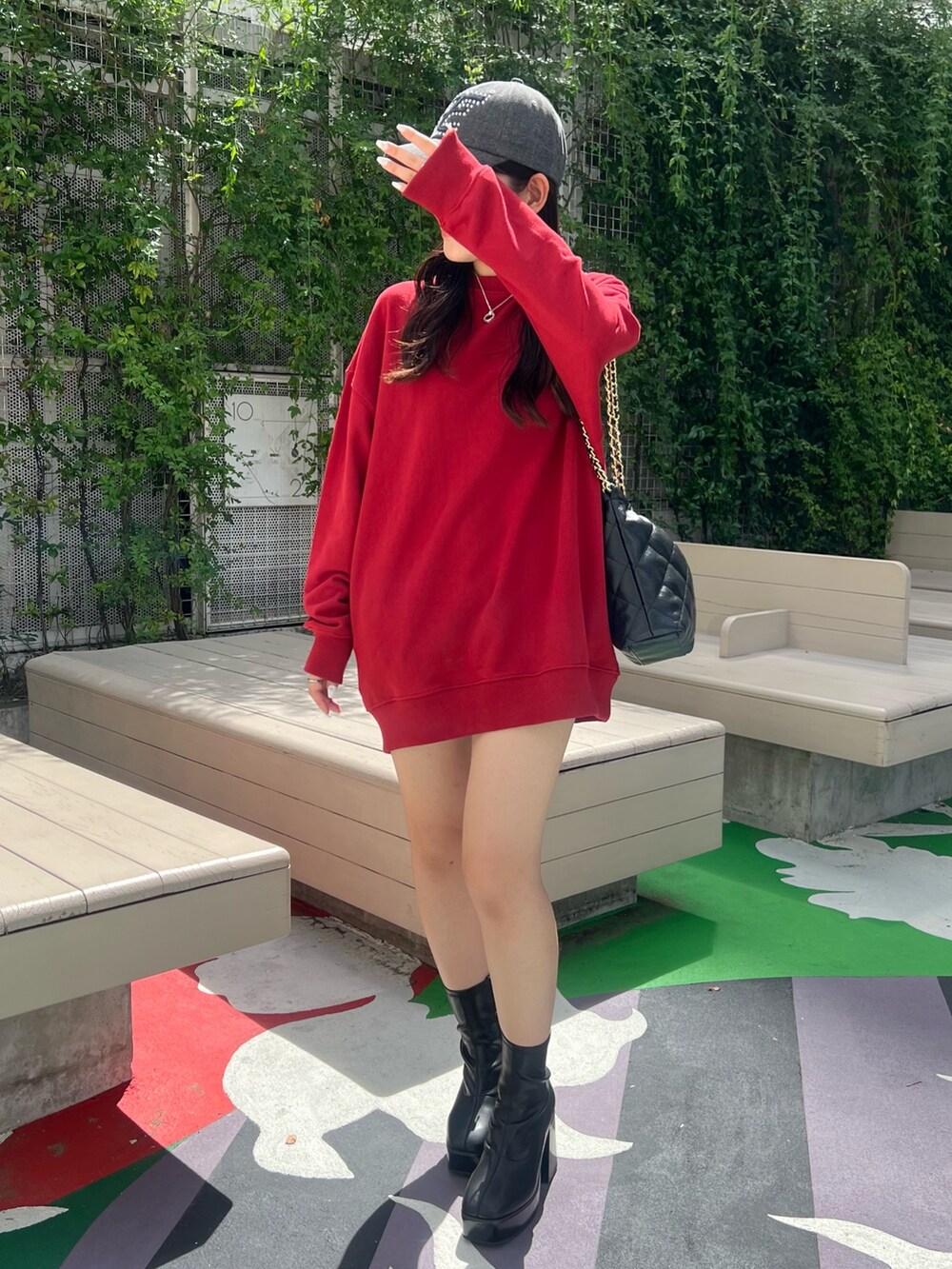 レッド系のスウェット、ブラック系のショルダーバッグ、ブラック系のブーツを着用したレディースの夏コーディネートの2枚目の写真