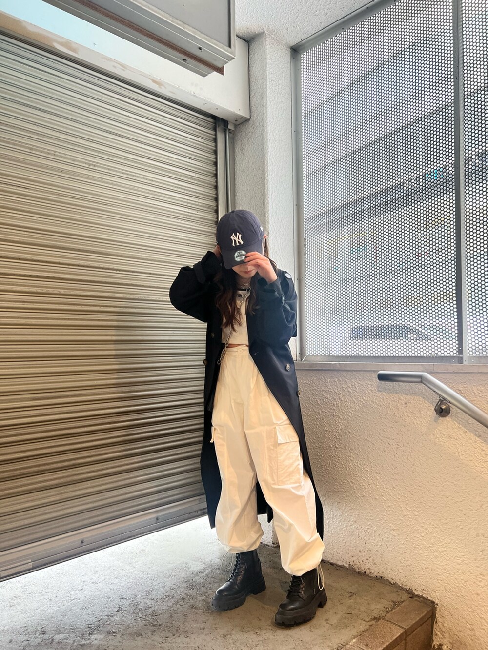 ブラック系のトレンチコート、ホワイト系のカーゴパンツ、ブラック系のショルダーバッグを着用したレディースの春コーディネートの2枚目の写真
