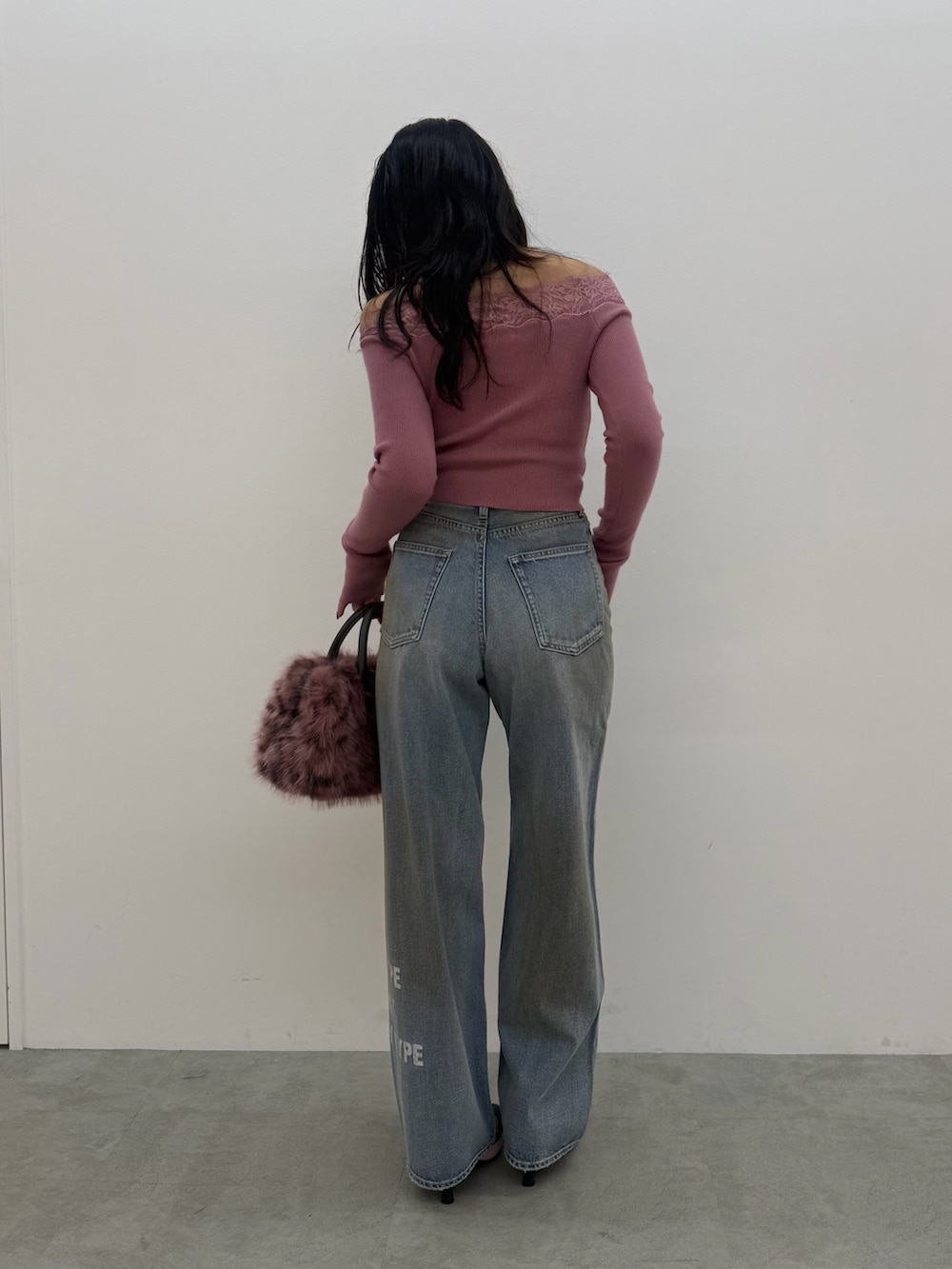 ピンク系のボストンバッグ、ピンク系のニット/セーター、ブルー系のデニムパンツを着用したレディースの秋コーディネートの3枚目の写真