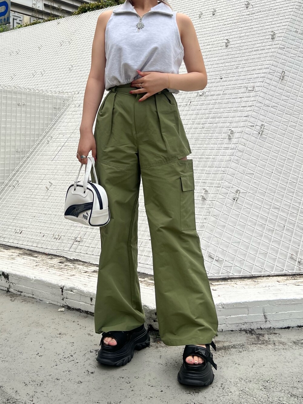 ホワイト系のハンドバッグ、グリーン系のカーゴパンツ、ブラック系のサンダルを着用したレディースの春コーディネートの2枚目の写真