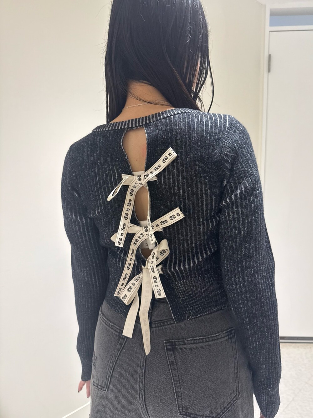 ブルー系のデニムパンツ、ブラック系のニット/セーター、ブラック系のブーツを着用したレディースの秋コーディネートの4枚目の写真