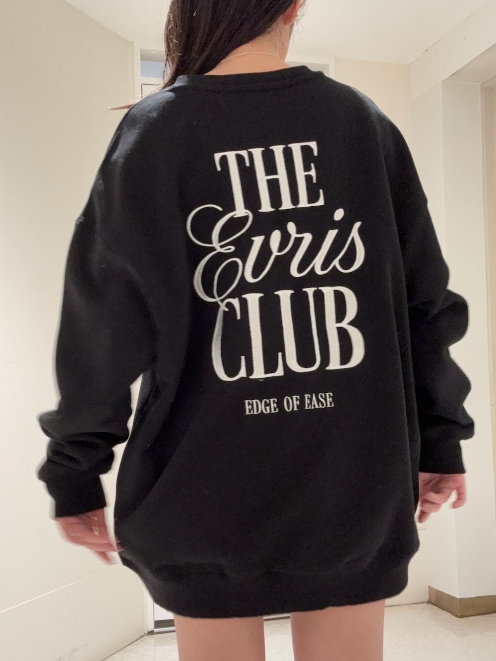 ブラック系のスウェット、ブラック系のブーツ、ブルー系のデニムパンツを着用したレディースの冬コーディネートの4枚目の写真