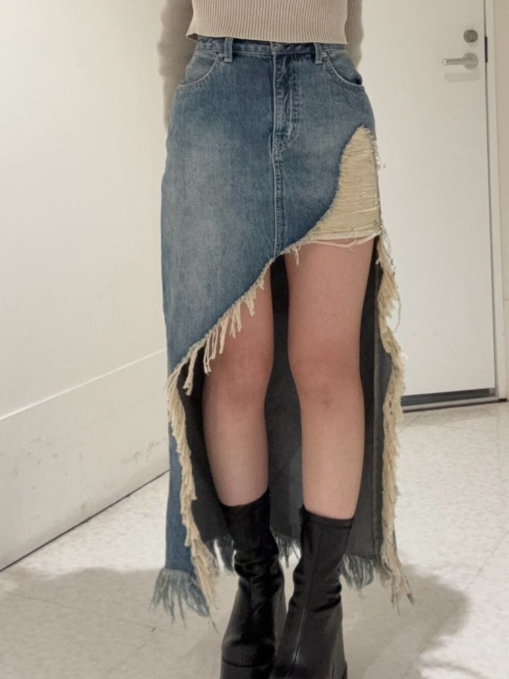 ブラック系のブーツ、ブルー系のデニムスカート、ベージュ系のニット/セーターを着用したレディースの春コーディネートの5枚目の写真