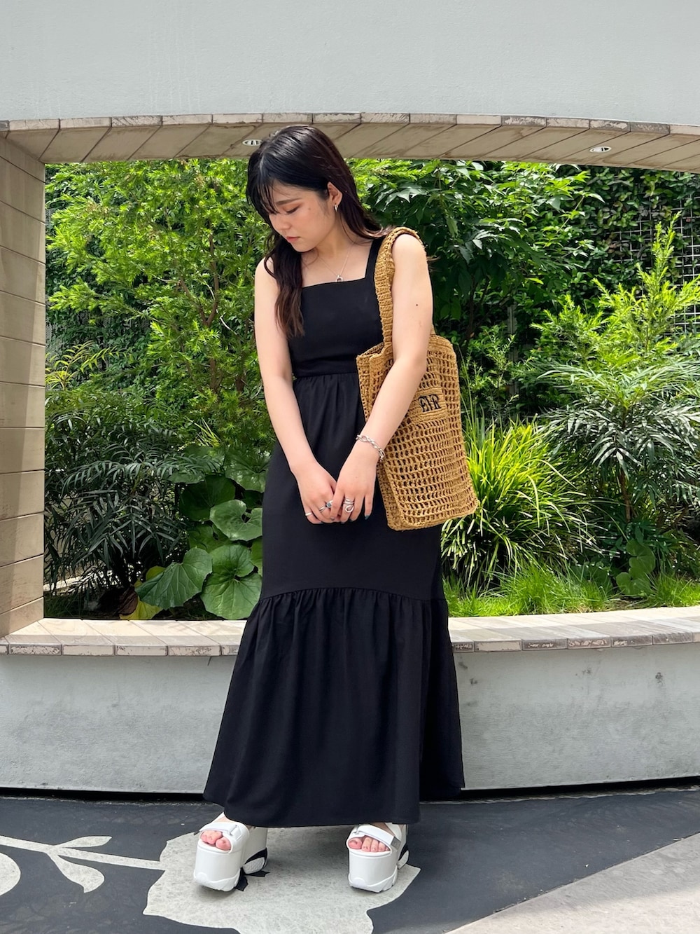 ブラック系のワンピース、ベージュ系のトートバッグ、ホワイト系のサンダルを着用したレディースの夏コーディネートの2枚目の写真