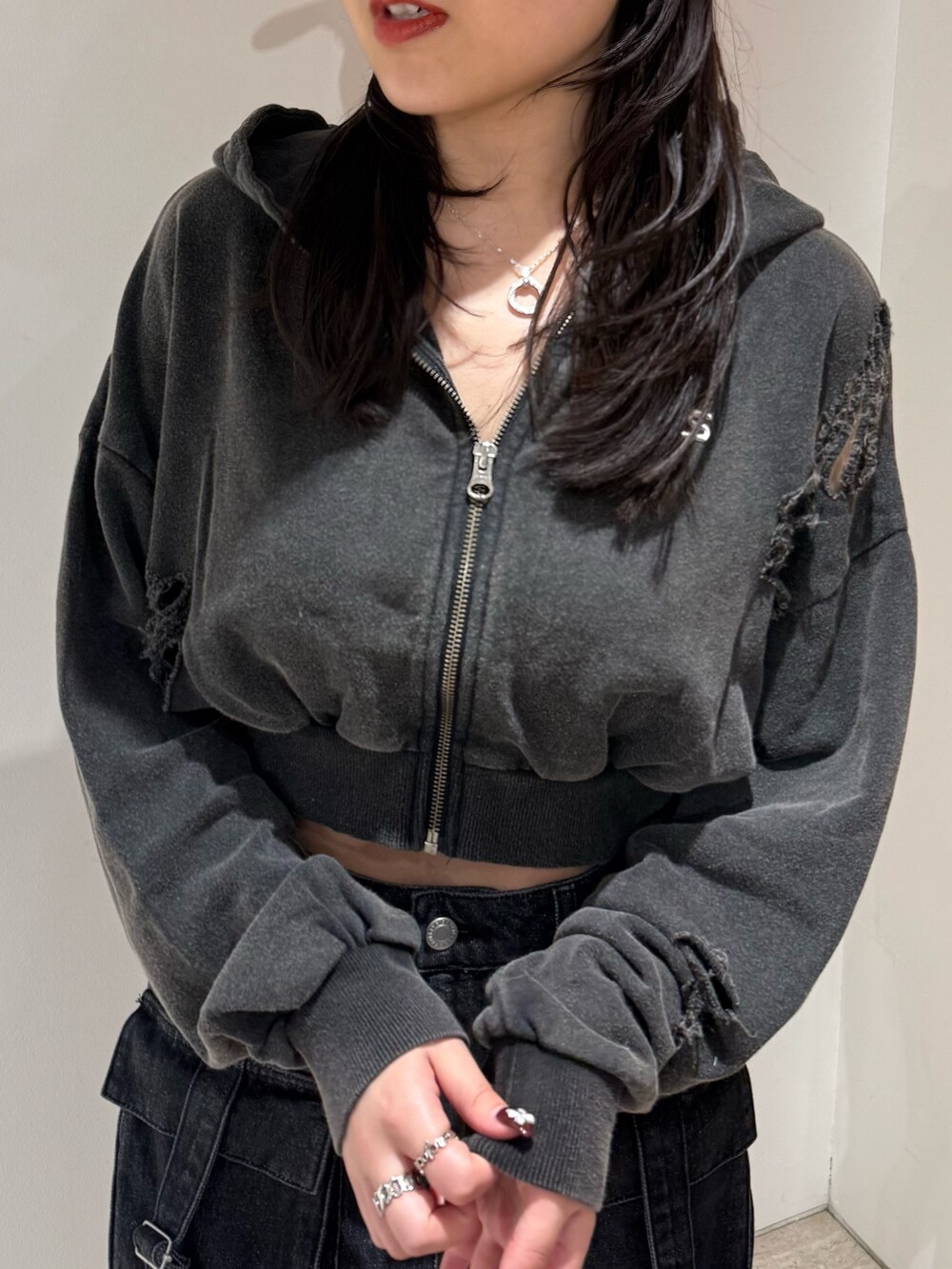 ブラック系のデニムスカート、ブラック系のブーツ、ブラック系のパーカーを着用したレディースの春コーディネートの4枚目の写真