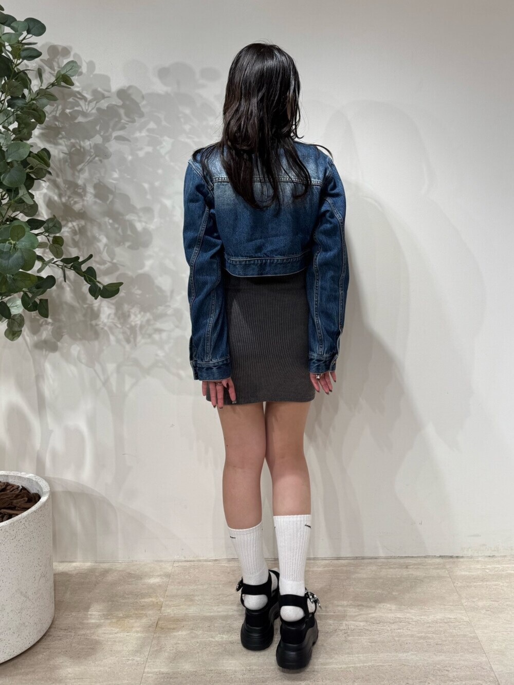 グレー系のワンピース、ブルー系のデニムジャケット、ブラック系のサンダルを着用したレディースの春コーディネートの3枚目の写真